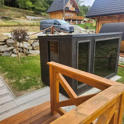 a small black house with a bench on a deck at Dom z Bali Zawoja z widokiem na Babią Górę in Stryszawa