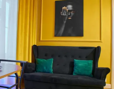 a black couch with two green pillows against a yellow wall at A cozy apartment in the heart of the city in Kraków