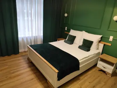 a bedroom with a large bed with green walls at A cozy apartment in the heart of the city in Kraków