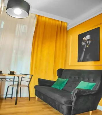 a living room with a black couch and a table at A cozy apartment in the heart of the city in Kraków