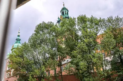 a tall building with trees in front of it at Exclusive Royal Apartments in Kraków