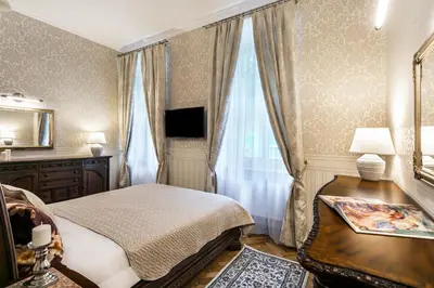 a bedroom with a bed and a desk and curtains at Exclusive Royal Apartments in Kraków