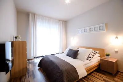 a bedroom with a bed and a large window at Apartments of Pawia in Kraków