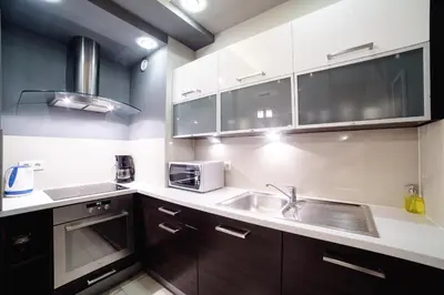 a kitchen with wooden cabinets and a sink and a microwave at Apartments of Pawia in Kraków