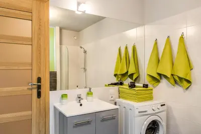a bathroom with a washing machine and a sink at Apartments of Pawia in Kraków