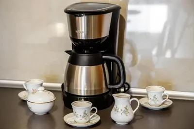 a coffee maker on a table with cups and saucers at Apartments of Pawia in Kraków
