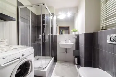 a bathroom with a shower and a sink and a washing machine at Apartments of Pawia in Kraków