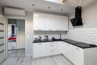 a kitchen with white cabinets and black counter tops at Central & comfortable apartment in Kraków