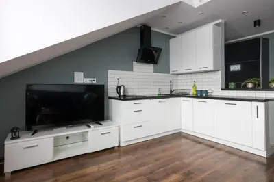 a kitchen with white cabinets and a flat screen tv at Elegant apartment 5 minutes from Wawel Castle in Kraków