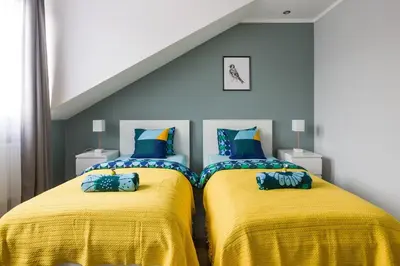 two beds in a room with yellow blankets and blue pillows at Elegant apartment 5 minutes from Wawel Castle in Kraków