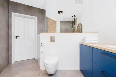 a bathroom with a white toilet and a blue cabinet at Apartament 3d Wilga by Noclegi Renters in Kraków