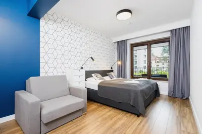 a bedroom with a bed and a chair at Apartament 3d Wilga by Noclegi Renters in Kraków