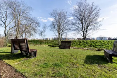 three park benches sitting in the grass in a park at Glossy Apart G73 in Kraków