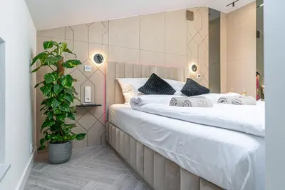 two white beds in a room with a potted plant at Dasto Jacuzzi Old Town Cracow in Kraków
