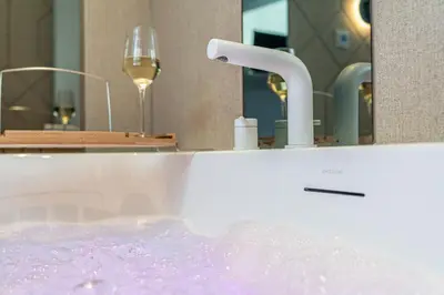 a bath tub with a wine glass and a faucet at Dasto Jacuzzi Old Town Cracow in Kraków