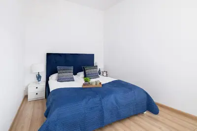 a bedroom with a blue bed and white walls at Dietla Apartament z Klimatyzacją i Balkonem w Centrum Krakowa by Noclegi Renters in Kraków