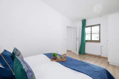 a bedroom with a white bed with blue pillows at Dietla Apartament z Klimatyzacją i Balkonem w Centrum Krakowa by Noclegi Renters in Kraków
