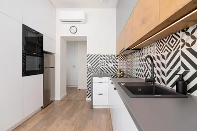 a kitchen with a sink and a black and white patterned wall at Kraków Studio Wawrzyńca by Noclegi Renters in Kraków