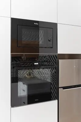 a black microwave oven in a white kitchen at Kraków Studio Wawrzyńca by Noclegi Renters in Kraków