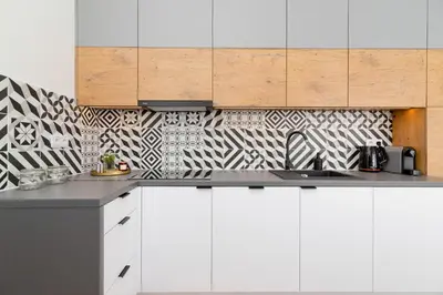 a kitchen with white cabinets and black and white tiles at Kraków Studio Wawrzyńca by Noclegi Renters in Kraków