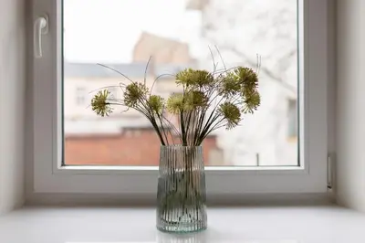 a vase filled with flowers sitting on a window sill at Kraków Studio Wawrzyńca by Noclegi Renters in Kraków