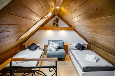 a attic room with two beds and a chair at Domek Kordoń SPA Jacuzzi & Sauna in Zubrzyca Górna