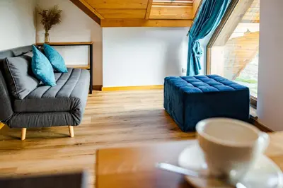 a living room with a couch and a blue ottoman at Domek Kordoń SPA Jacuzzi & Sauna in Zubrzyca Górna