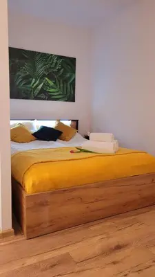 a bedroom with a bed with yellow sheets and a painting at Apartament Joanna in Wadowice