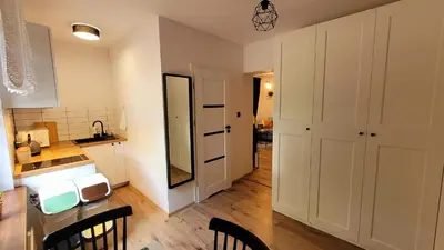 a kitchen with white cabinets and a counter with chairs at Apartament Joanna in Wadowice