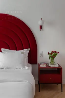 a bed with a red headboard and a table with a vase of flowers at Colorful 2-bed, 100sqm apartment in the heart of Kazimierz in Kraków