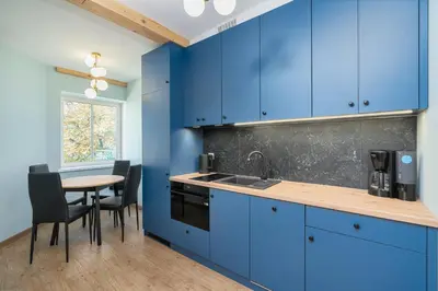 a kitchen with blue cabinets and a table with chairs at Dietla ANTA Apartment in Kraków