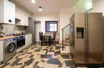 a kitchen with a refrigerator and a table with chairs at Pokoje na Sowiej in Kraków