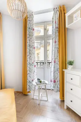 a bedroom with yellow curtains and a table at ANTA Apartments Plac na Groblach in Kraków