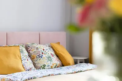 a bed with colorful pillows and a pink headboard at ANTA Apartments Plac na Groblach in Kraków