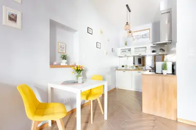 a kitchen with a white table and yellow chairs at ANTA Apartments Plac na Groblach in Kraków