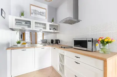 a kitchen with white cabinets and a counter with a microwave at ANTA Apartments Plac na Groblach in Kraków