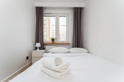 a white bedroom with two beds and a window at Pachońskiego Urban Chic Apartment by BookingHost in Kraków