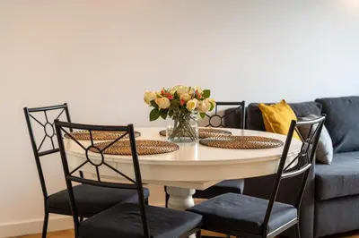 a dining room table with chairs and a vase of flowers at Pachońskiego Urban Chic Apartment by BookingHost in Kraków