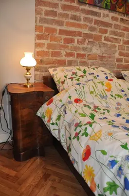 a bed with a comforter with flowers on it at Krakowsky Apartment in Kraków