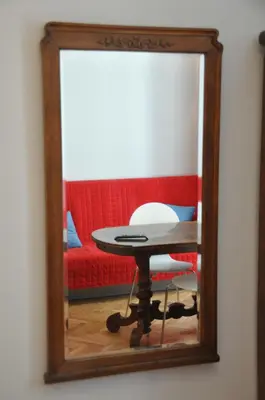 a mirror reflecting a table and a red couch at Krakowsky Apartment in Kraków