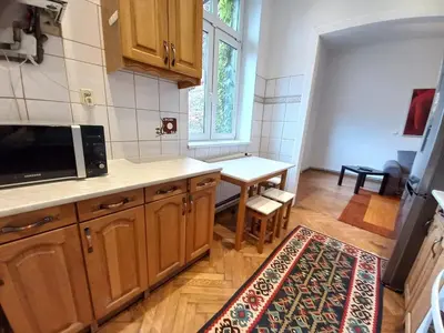 a kitchen with wooden cabinets and a table and a window at Old Town - 3 bedrooms Sołtyka S4 in Kraków