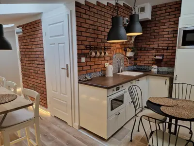 a kitchen with a brick wall and a table and chairs at NestingHigh apartment in Kraków