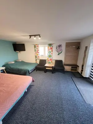 a hotel room with two beds and a living room at Apartamencik Pod Krokusem 2 in Rabka