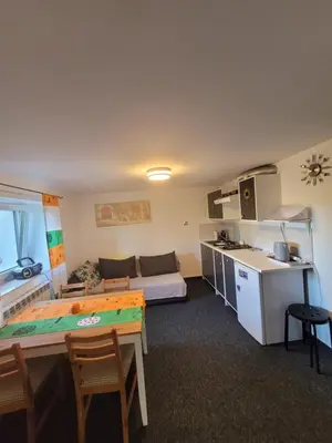 a room with a kitchen and a living room with a table at Apartamencik Pod Krokusem 2 in Rabka