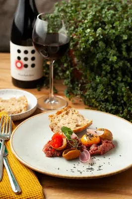 a table with a plate of food and a glass of wine at Hotel Dobczyce in Dobczyce