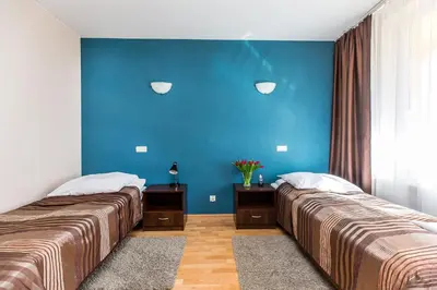 two beds in a room with a blue wall at Hotel Dobczyce in Dobczyce