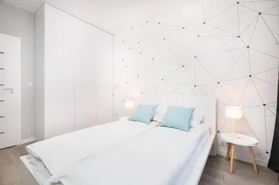 a white bedroom with a white bed with blue pillows at City of the Kings-Milford Sound in Kraków