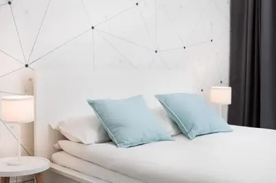a white bed with two blue pillows on it at City of the Kings-Milford Sound in Kraków