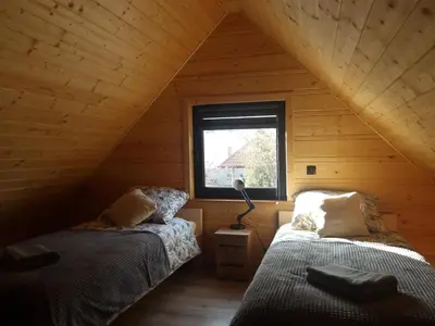 two beds in a log cabin with a window at Domki na Stodoliskach in Kasinka Mala