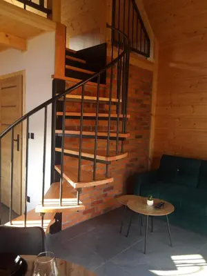 a spiral staircase in a room with a couch and a table at Domki na Stodoliskach in Kasinka Mala